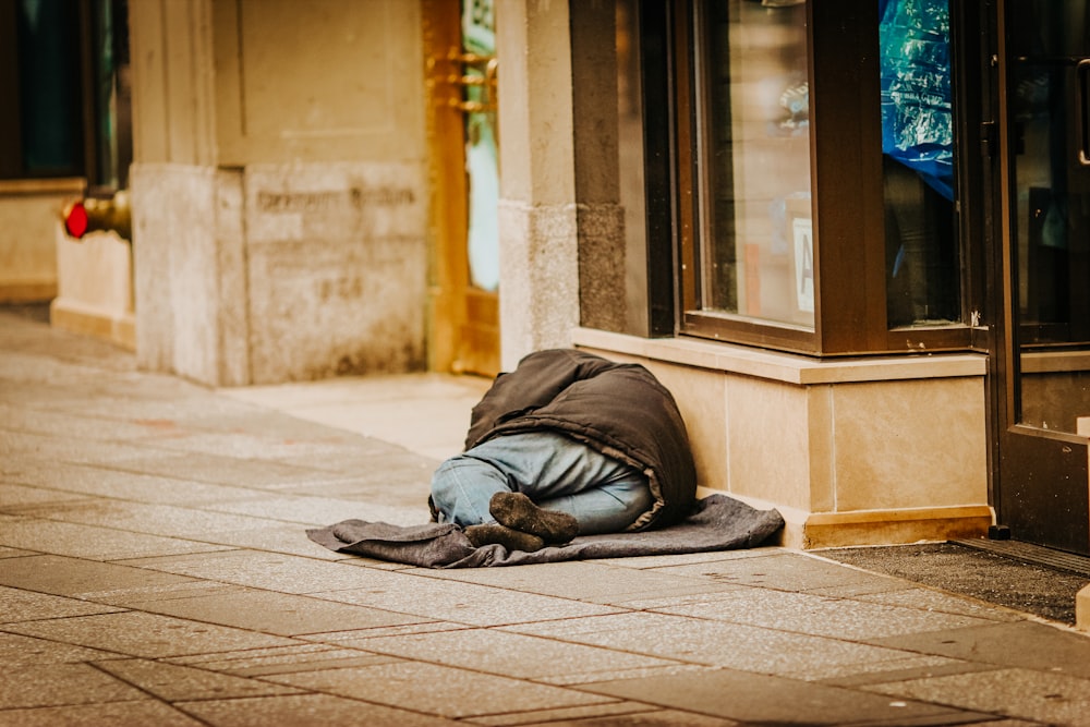 homme en sweat à capuche gris couché sur un sol en béton gris pendant la journée