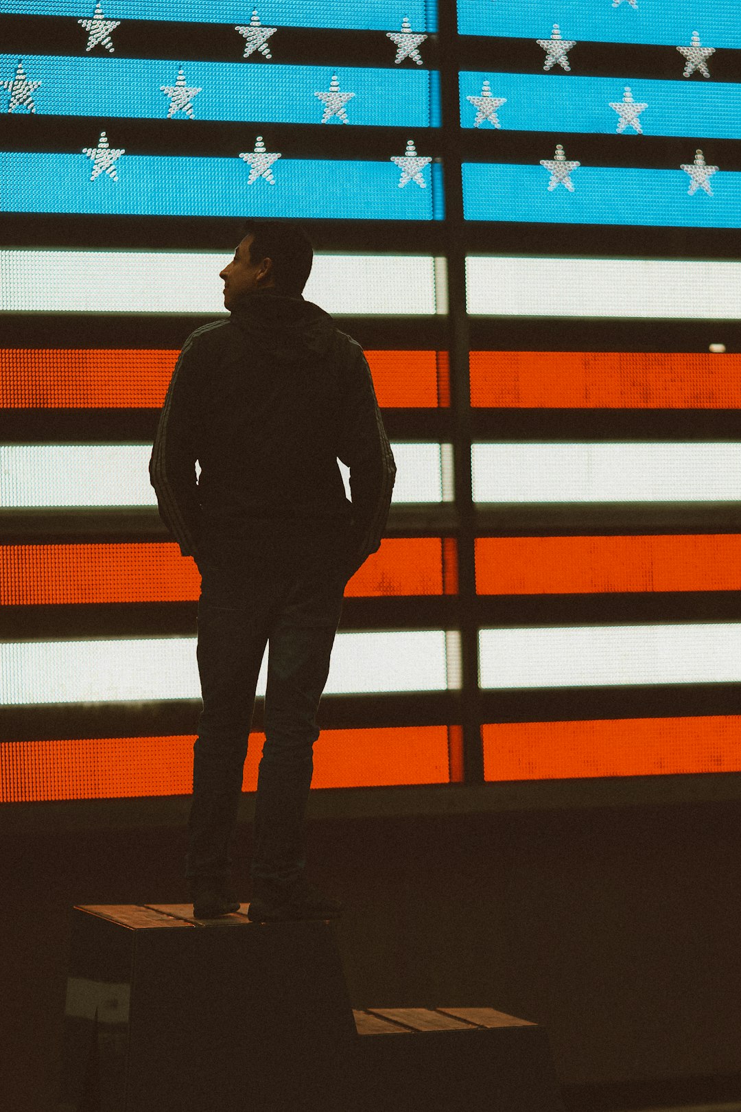 man in black jacket standing near red yellow and blue wall