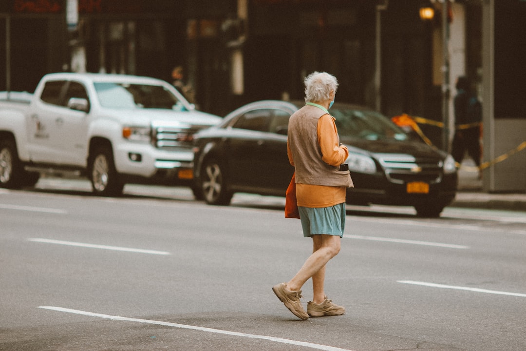 woman in orange shirt and blue denim shorts standing on road during daytime