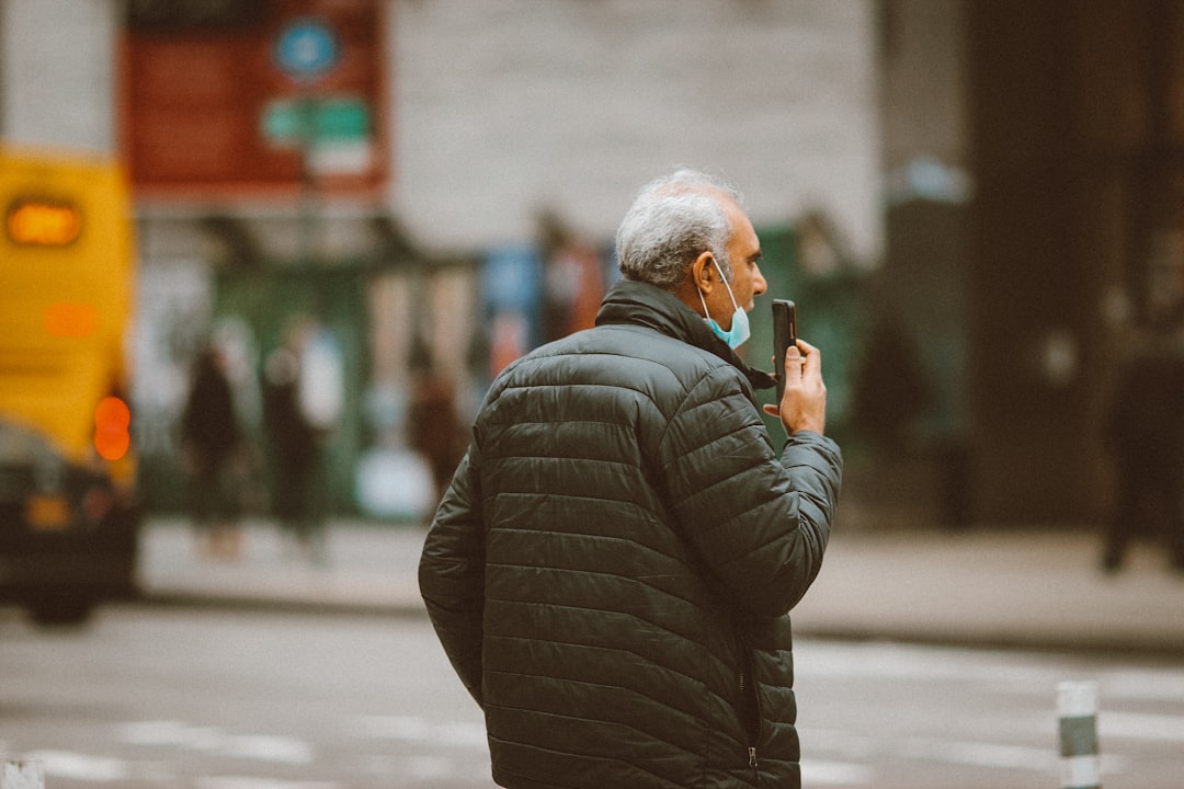 man in black bubble jacket using smartphone