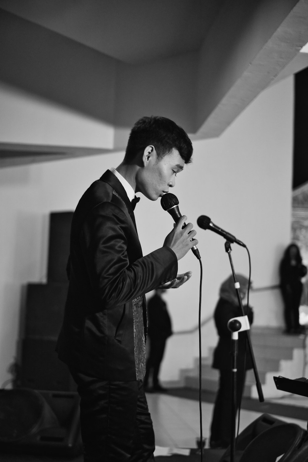 man in black suit singing on stage