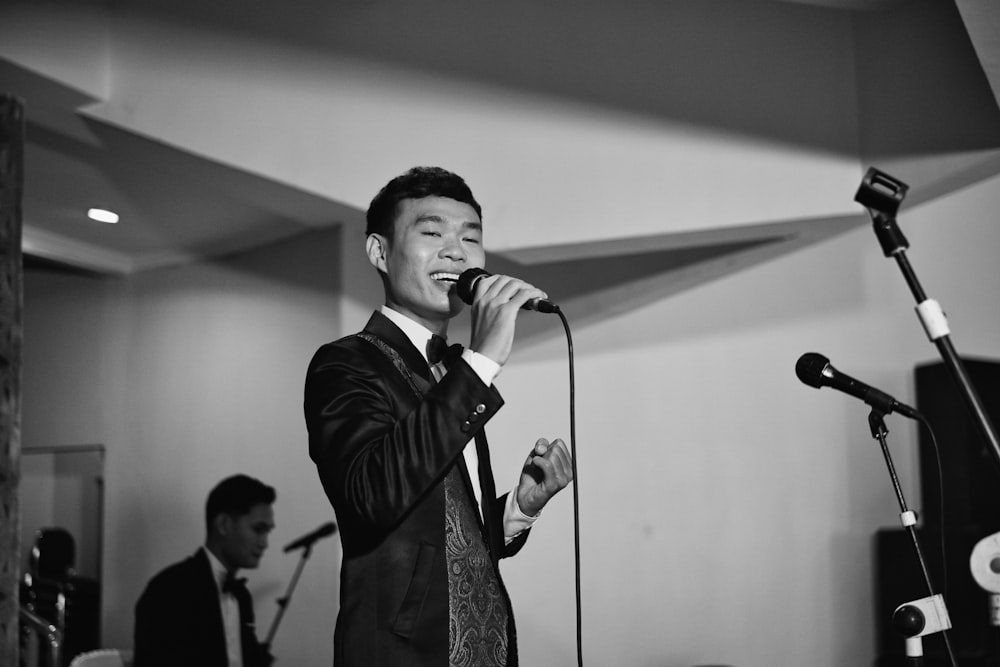 man in black suit singing on stage