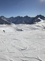 A snowy mountain landscape with clear blue skies and skiers enjoying the slopes.