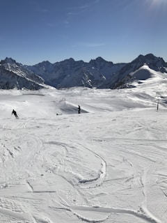 A snowy mountain landscape with clear blue skies and skiers enjoying the slopes.