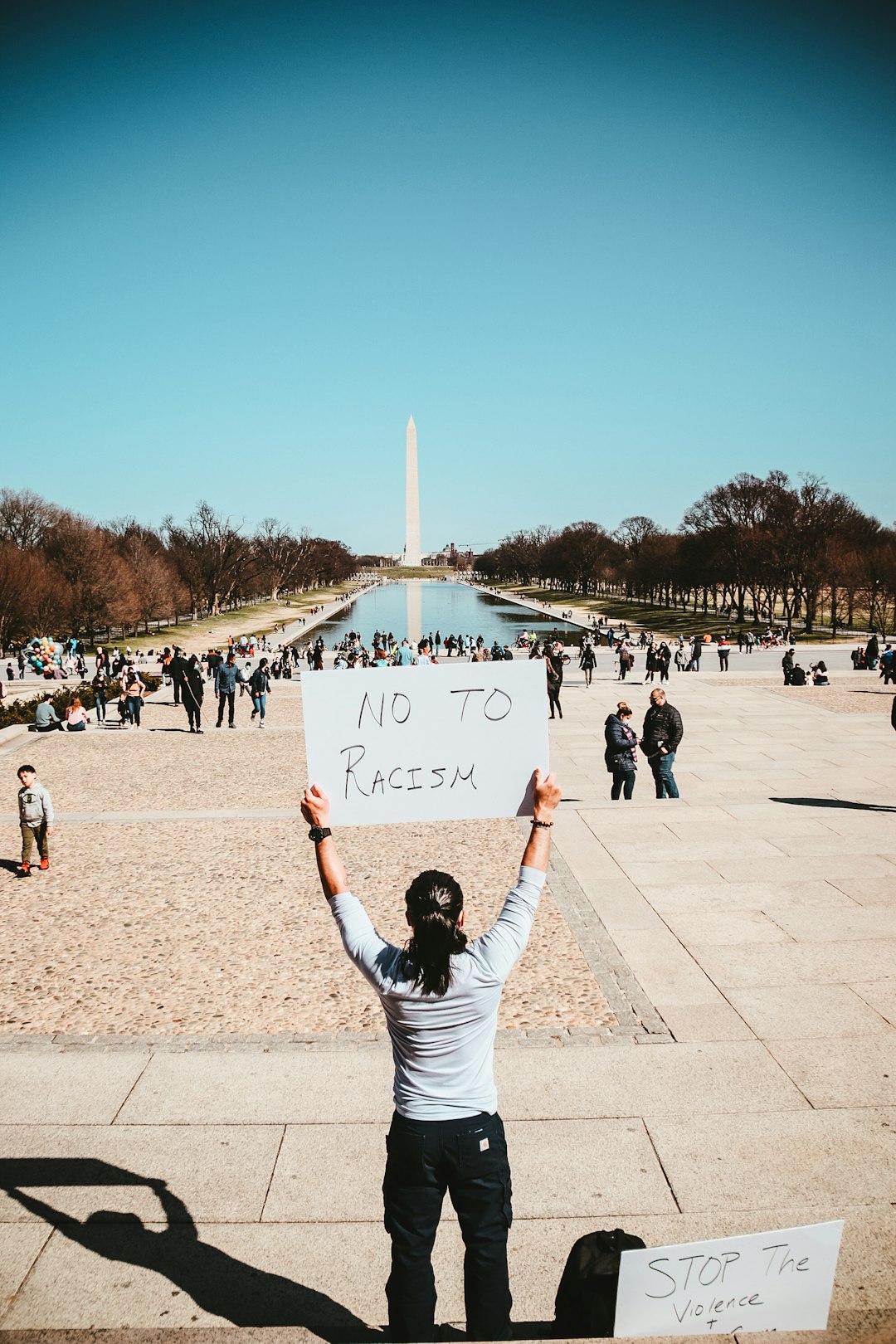 man in white t-shirt holding white and blue signage