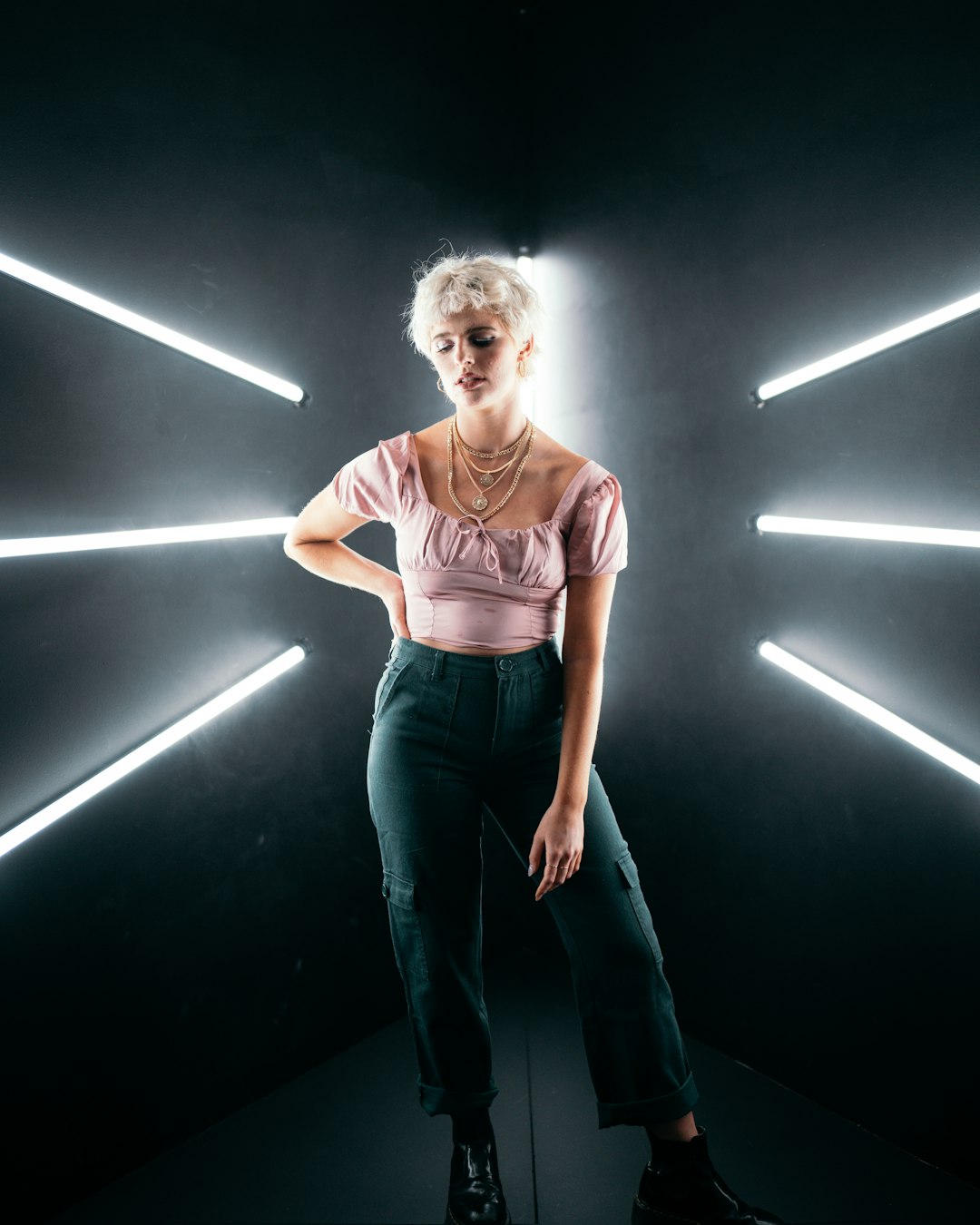 woman in pink scoop neck t-shirt and blue denim jeans standing beside white wall