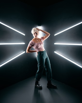 Confident blonde woman in leather outfit posing teasingly in neon cyberpunk style with blue and pink lights.