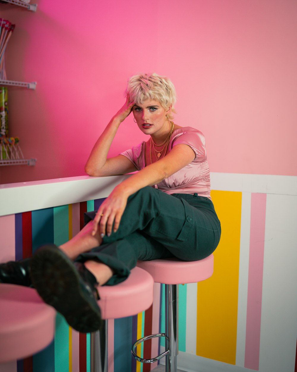 woman in pink shirt and black pants sitting on white and pink wooden chair
