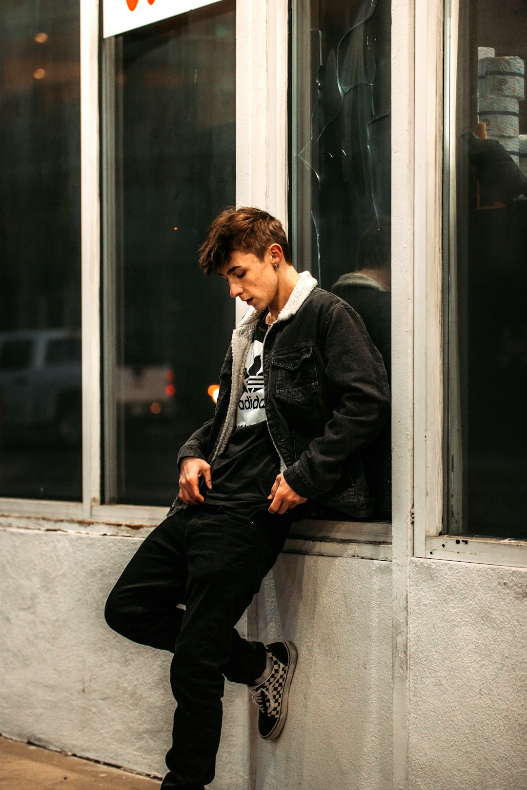 man in black suit jacket and black pants sitting on window