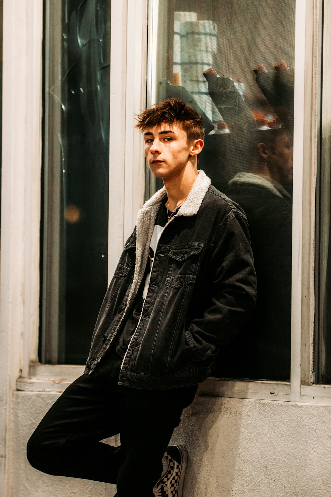 man in black leather jacket standing beside glass window