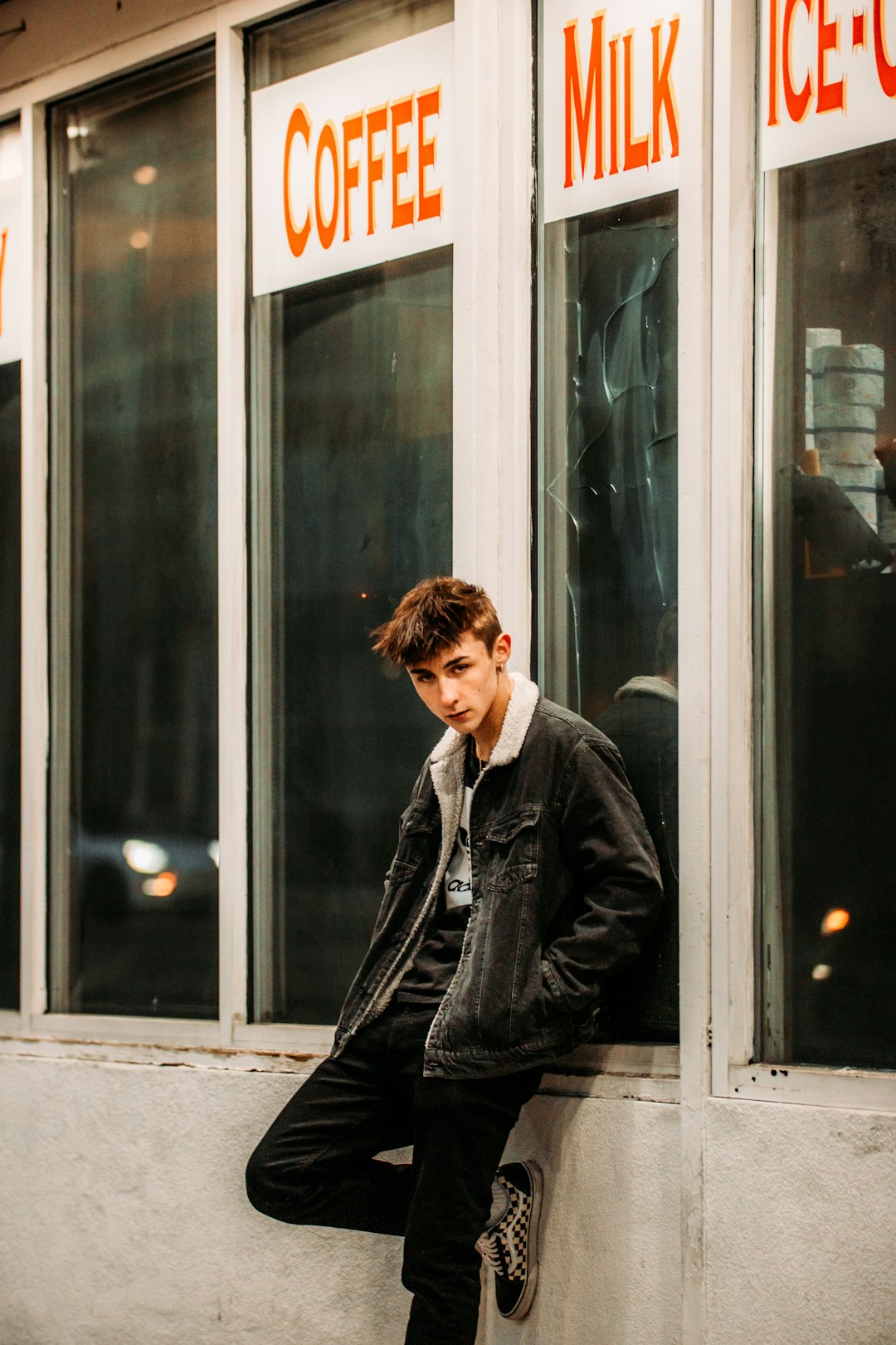 man in black leather jacket sitting on the window