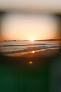 A serene beach at sunset, with gentle waves lapping against smooth sand.