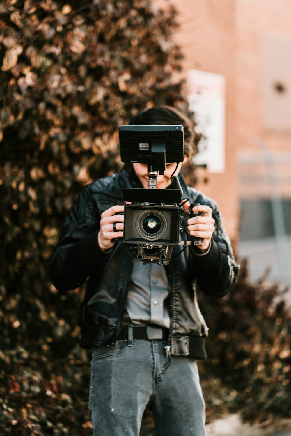 man in black jacket holding black camera