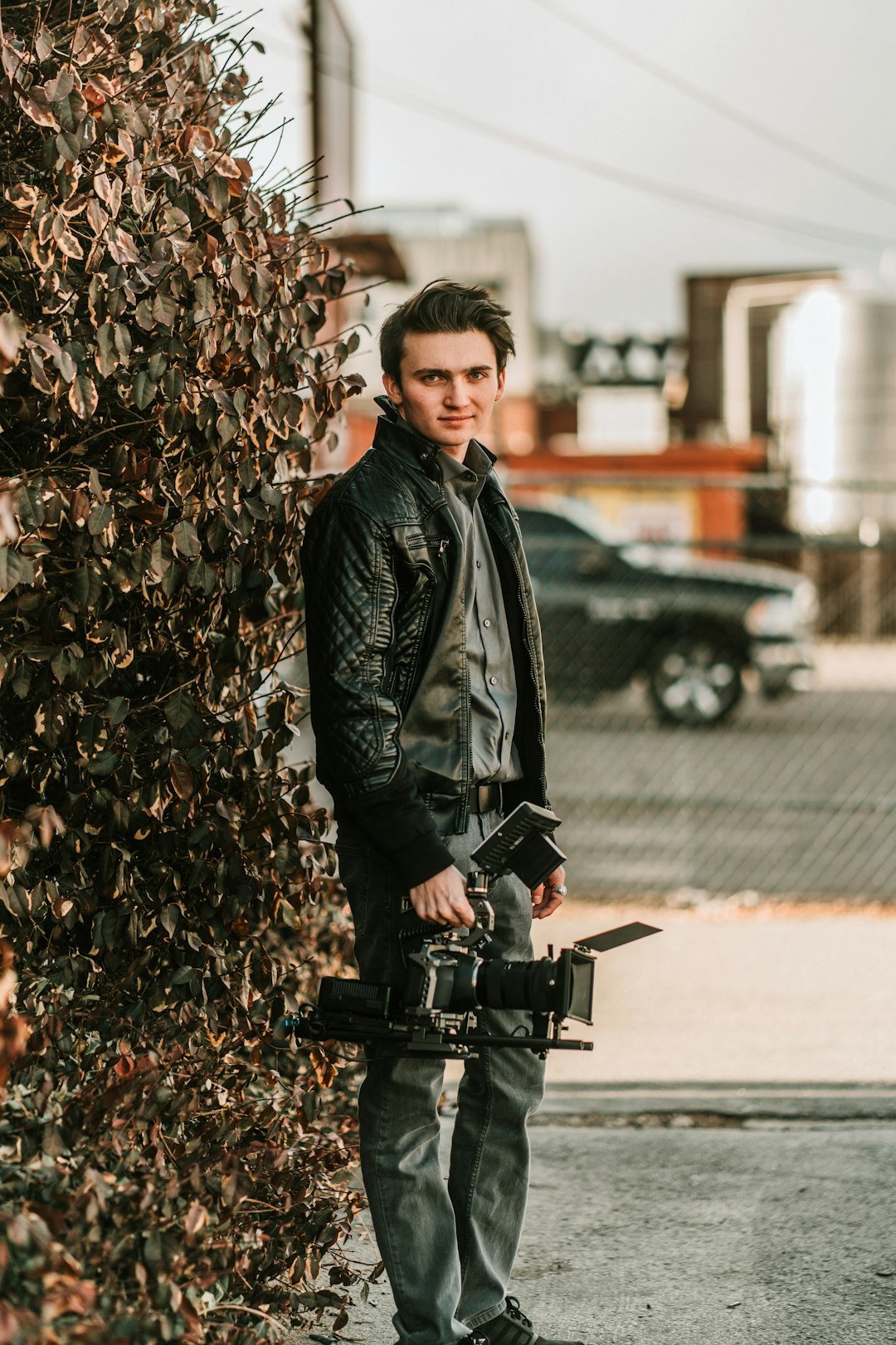 woman in black leather jacket standing beside brown tree during daytime