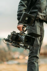 man in black jacket holding black dslr camera