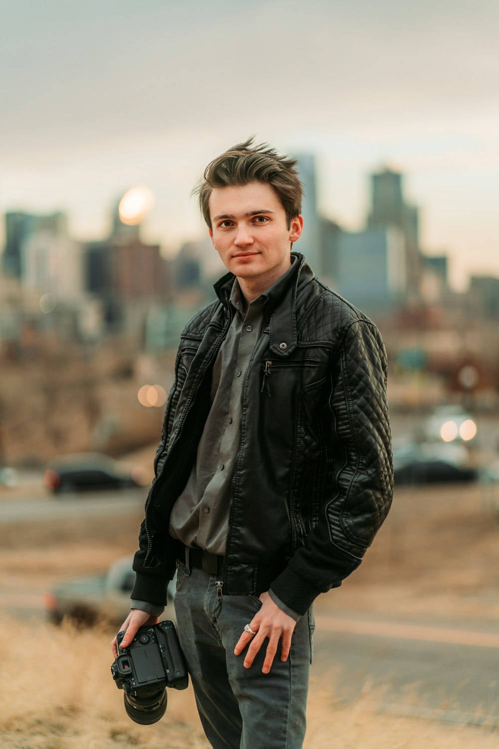 boy in black leather jacket standing on brown field during daytime