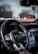 The interior of a luxury car featuring a detailed view of the steering wheel with the Mercedes-Benz logo prominently displayed. The dashboard includes modern controls and a digital display, and there is a view of the snowy landscape and trees outside through the windshield.