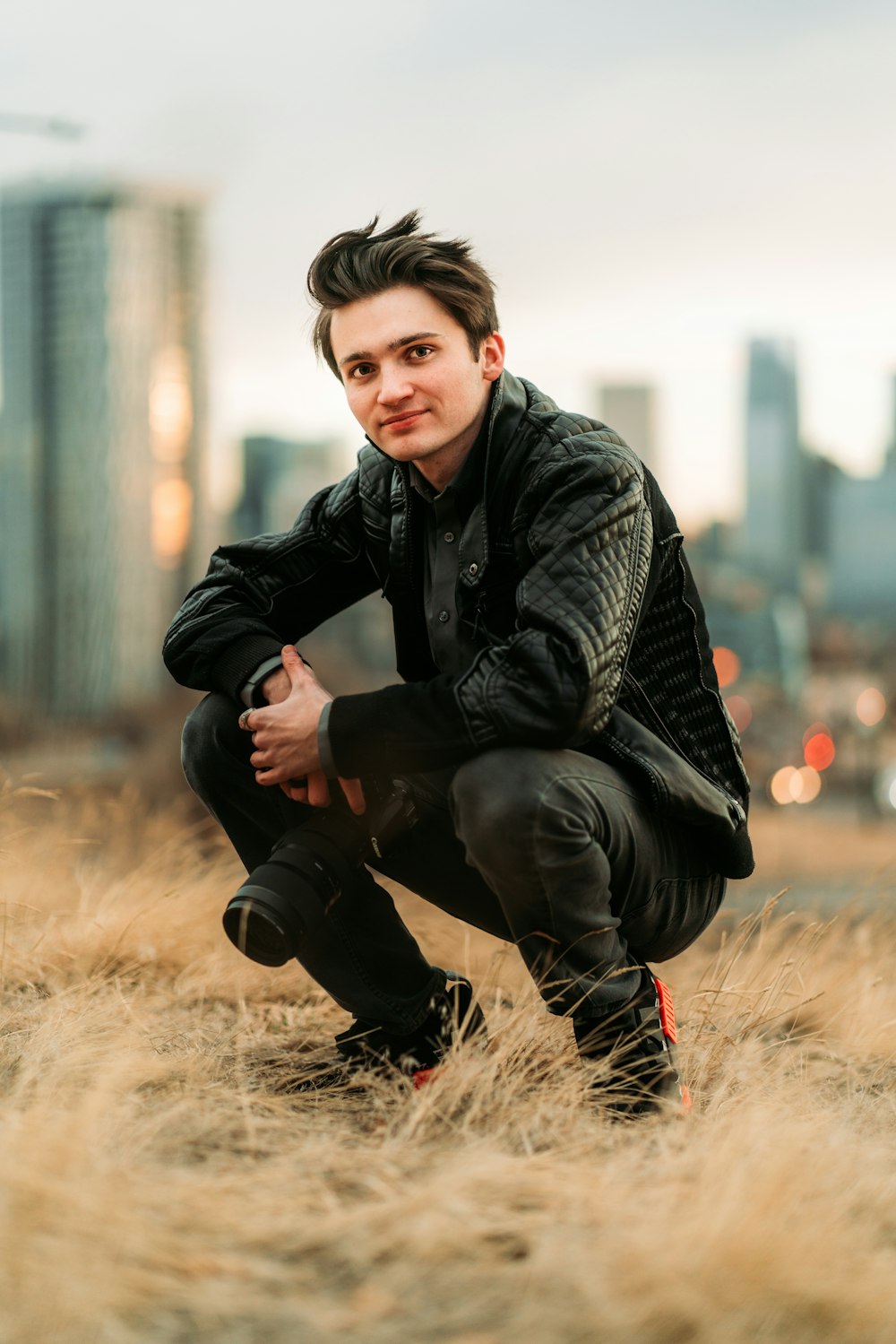 boy in black and gray jacket sitting on brown grass during daytime