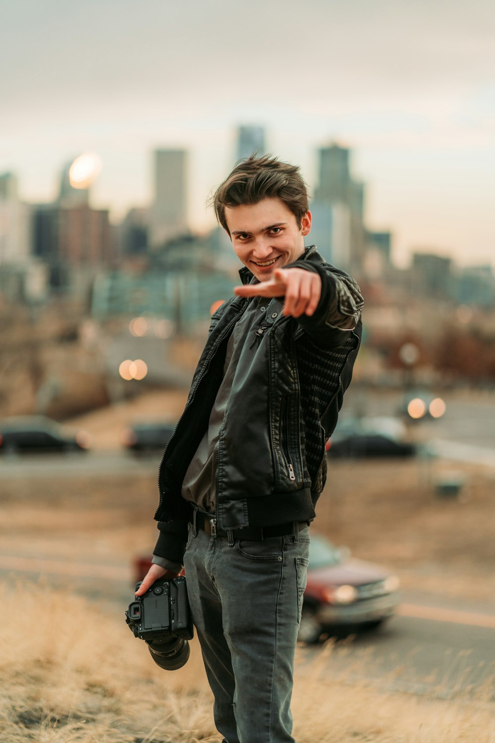 boy in black leather jacket and blue denim jeans standing on green grass field during daytime