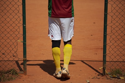 person in red shirt and yellow shorts standing on brown field