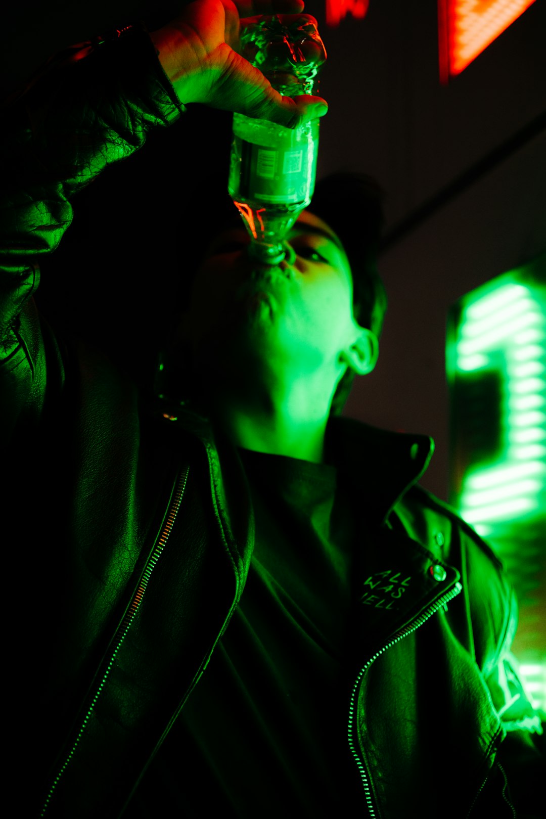man in black leather jacket holding green bottle