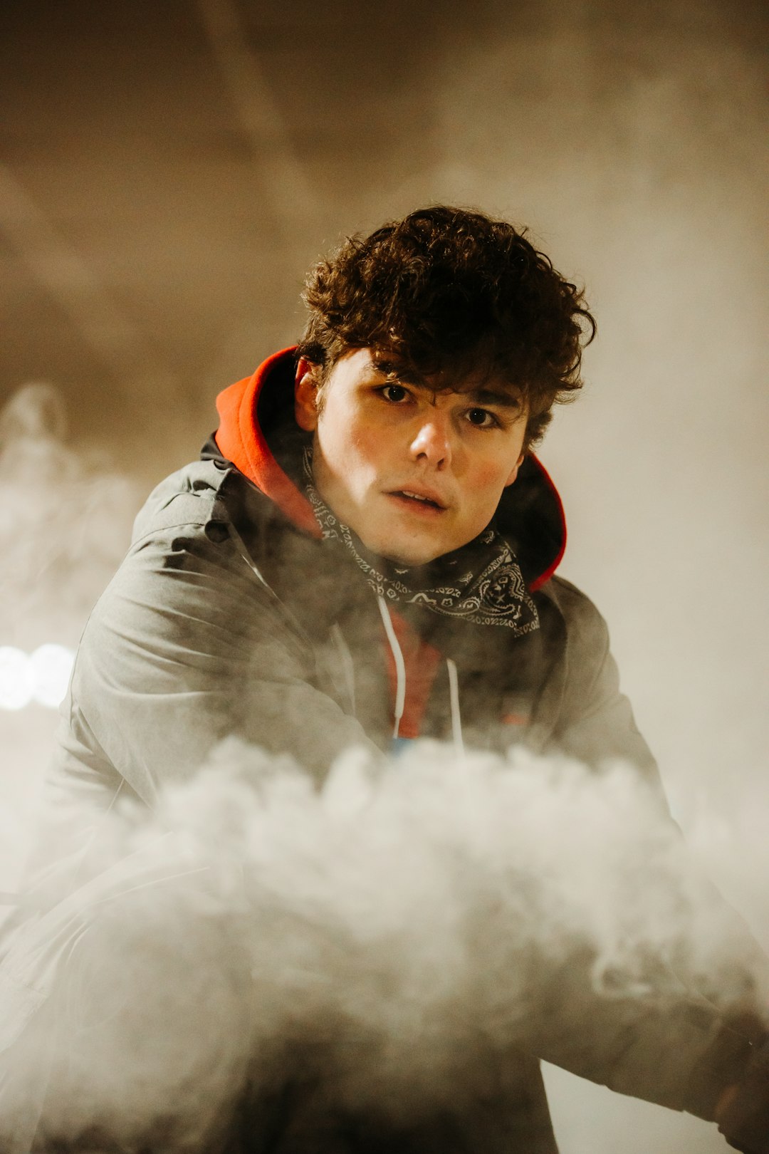 boy in black and red hoodie blowing white smoke