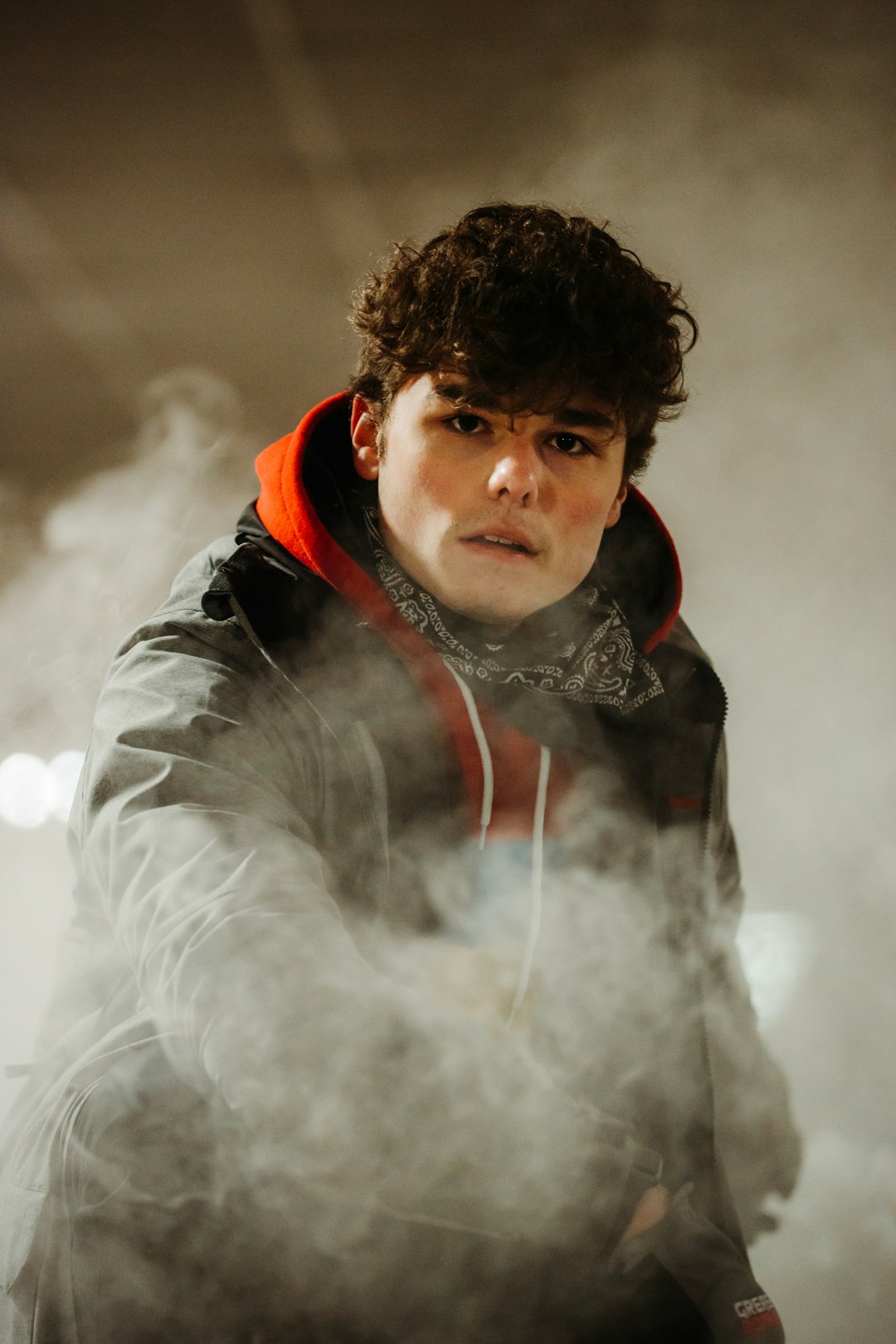 boy in black and red hoodie covered with white smoke