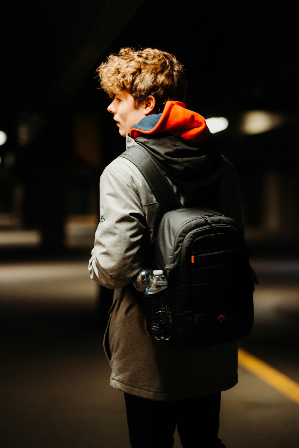 man in gray coat carrying black backpack