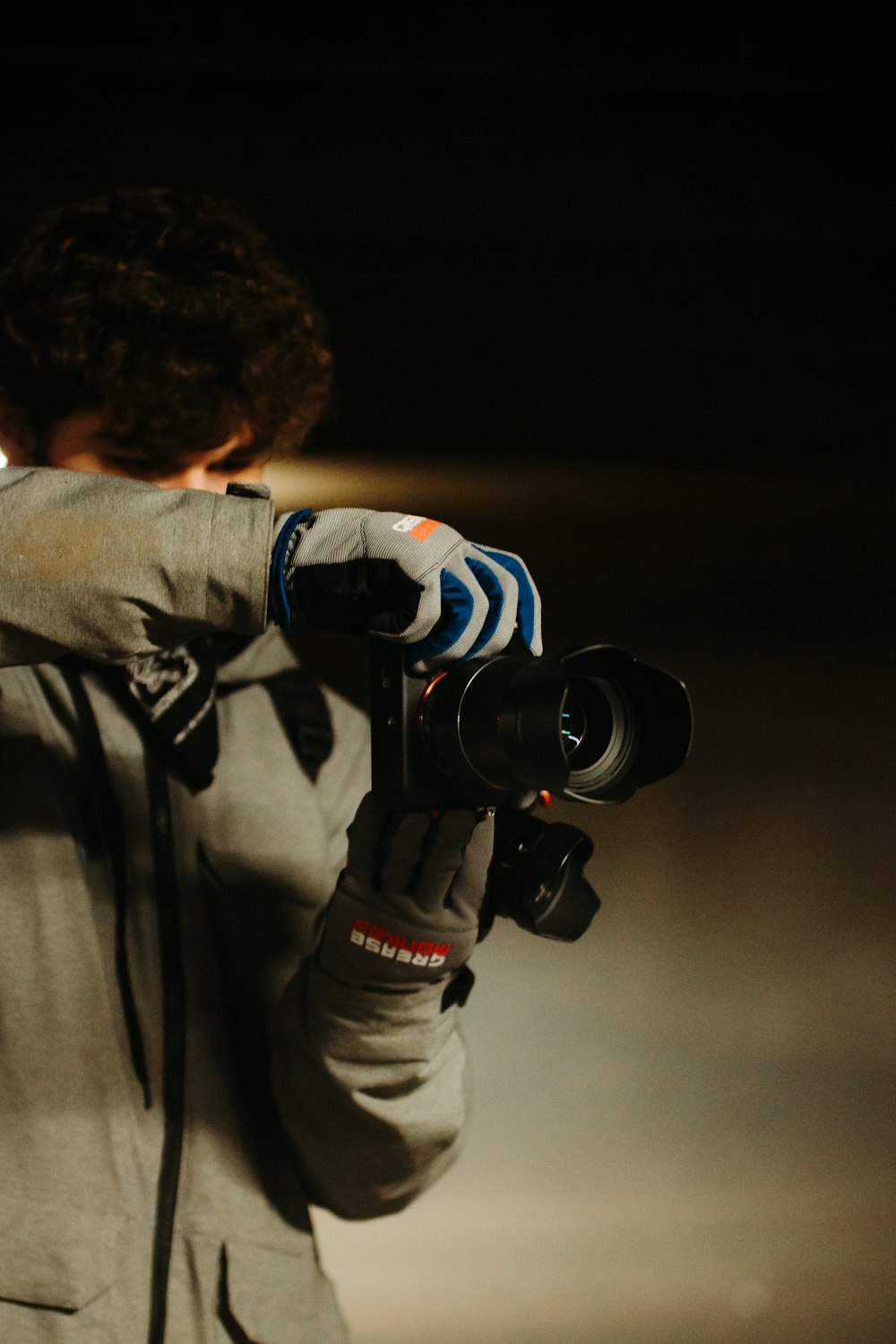 Hombre con chaqueta gris sosteniendo una cámara DSLR negra