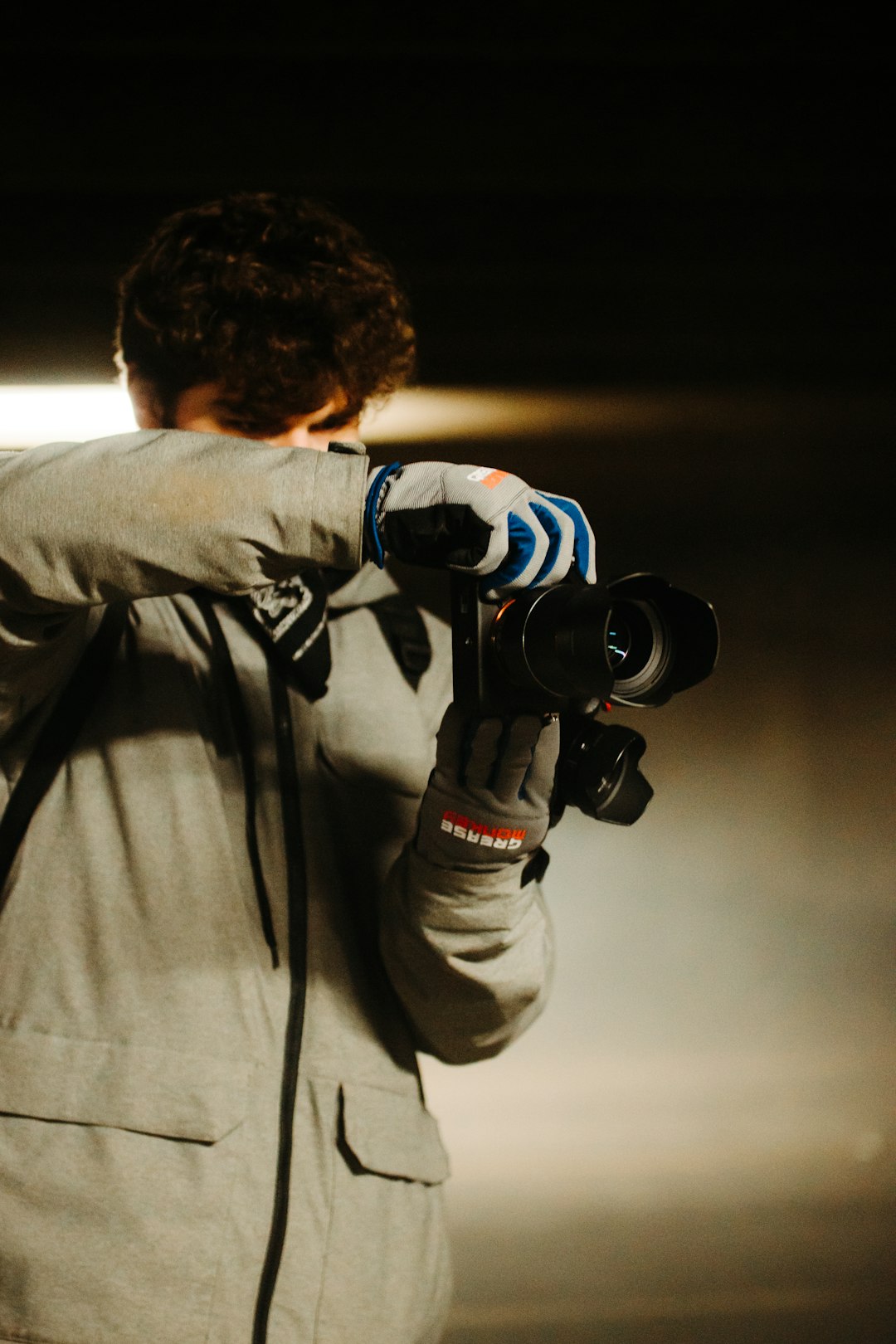 man in gray jacket holding black dslr camera