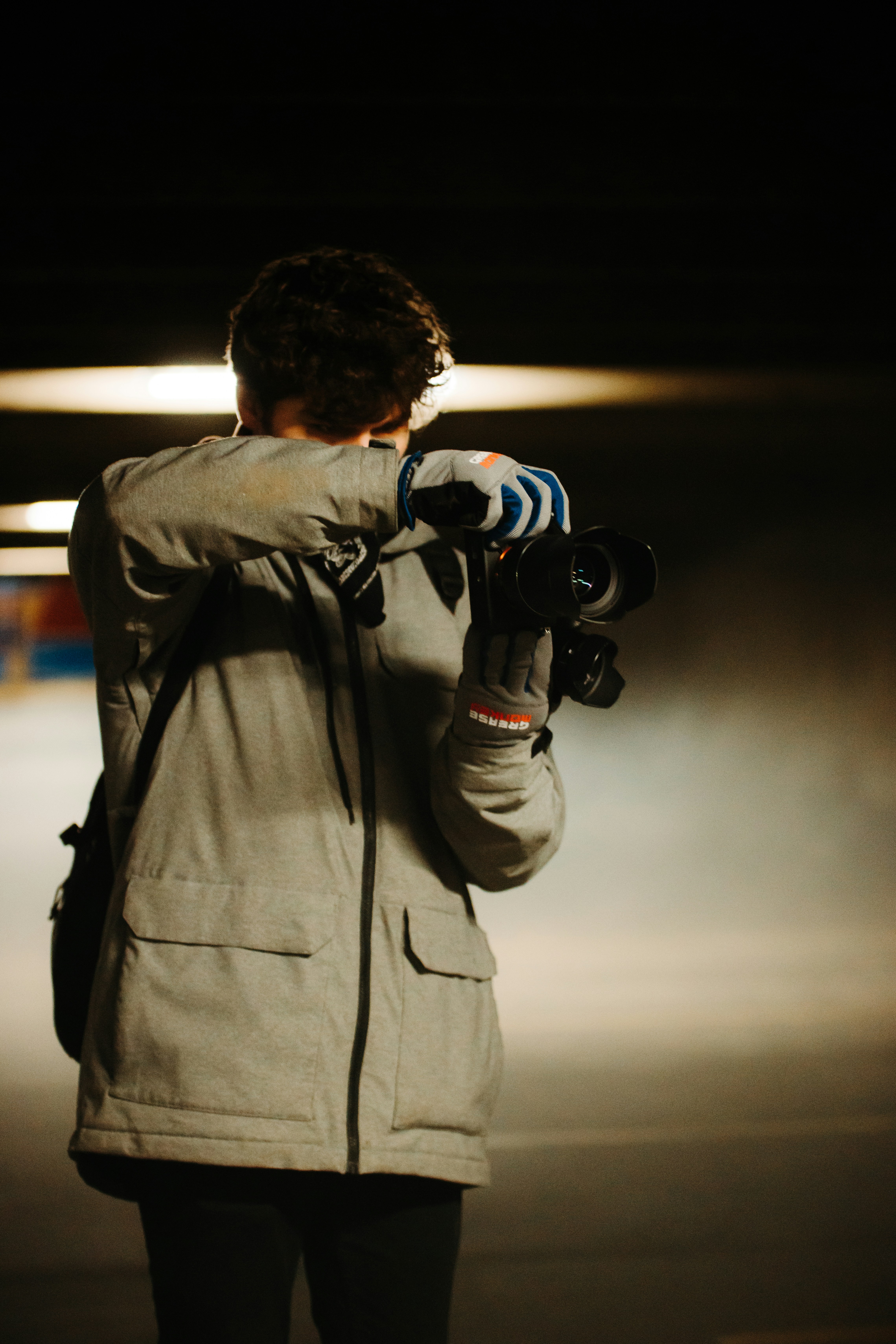 Hombre con chaqueta gris sosteniendo una cámara DSLR negra