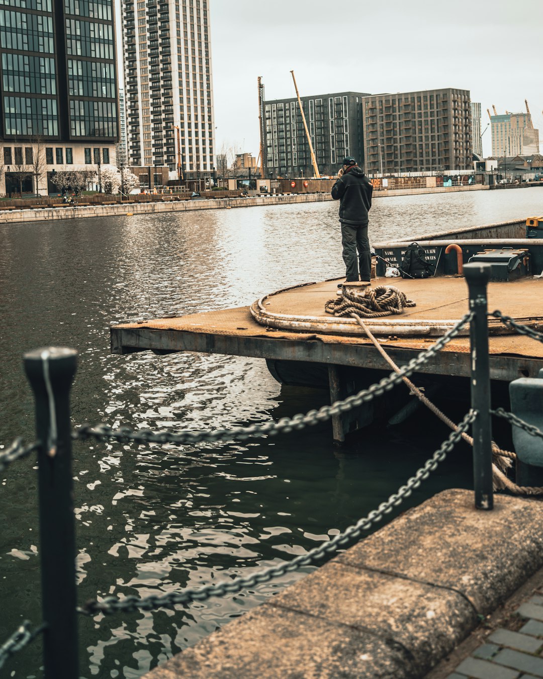 man in black jacket and pants standing on brown wooden dock during daytime