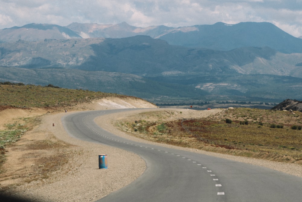 gray asphalt road near green grass field and mountains during daytime