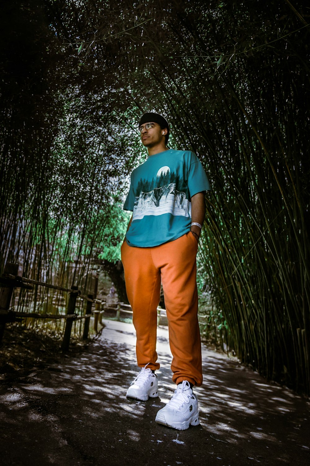 man in blue crew neck t-shirt and brown pants standing on wooden pathway