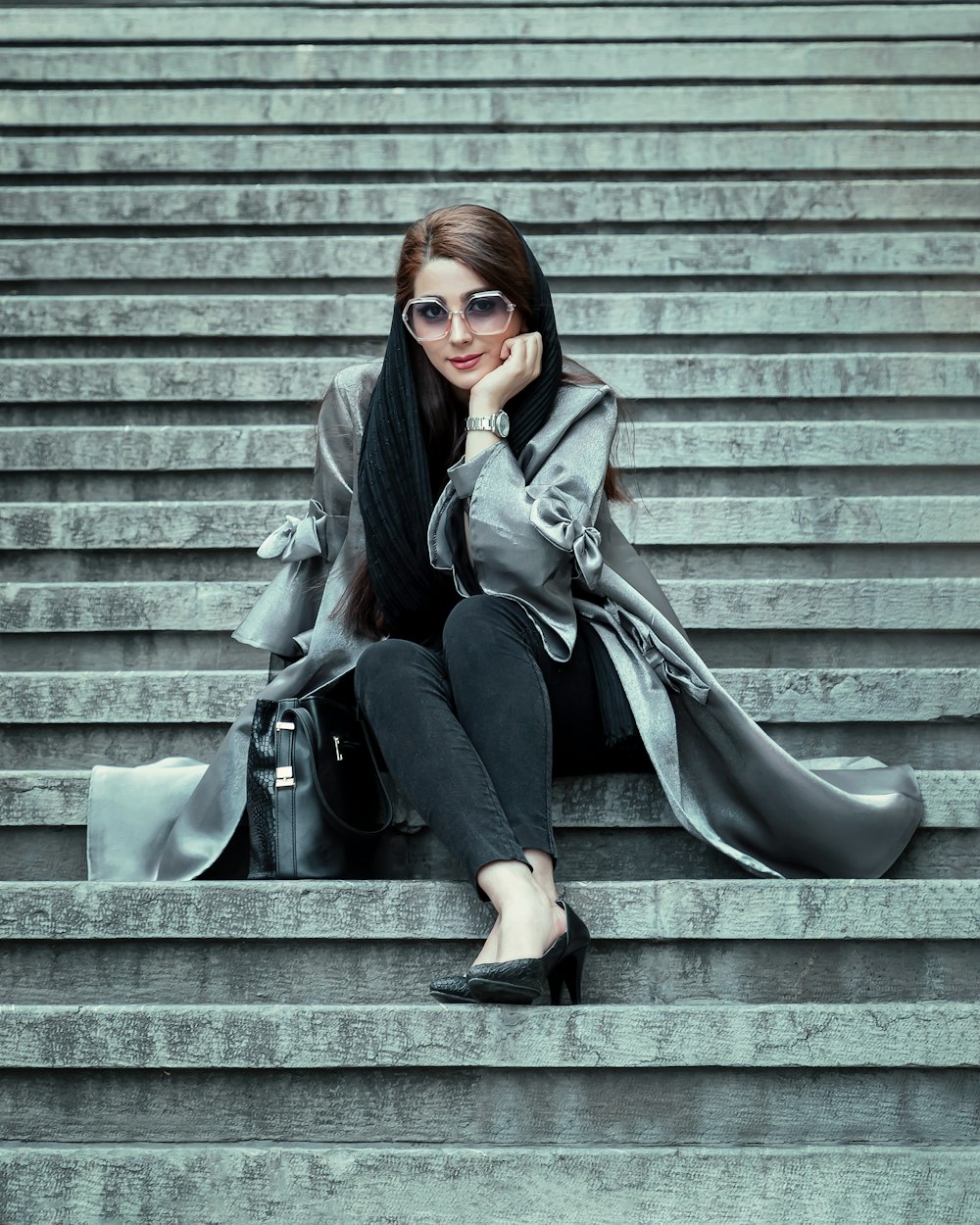 woman in black jacket and black pants sitting on gray concrete stairs
