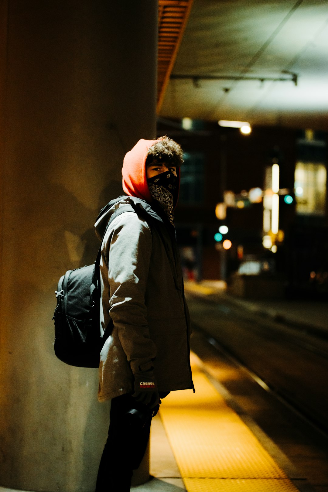man in brown jacket standing in the middle of the street during night time