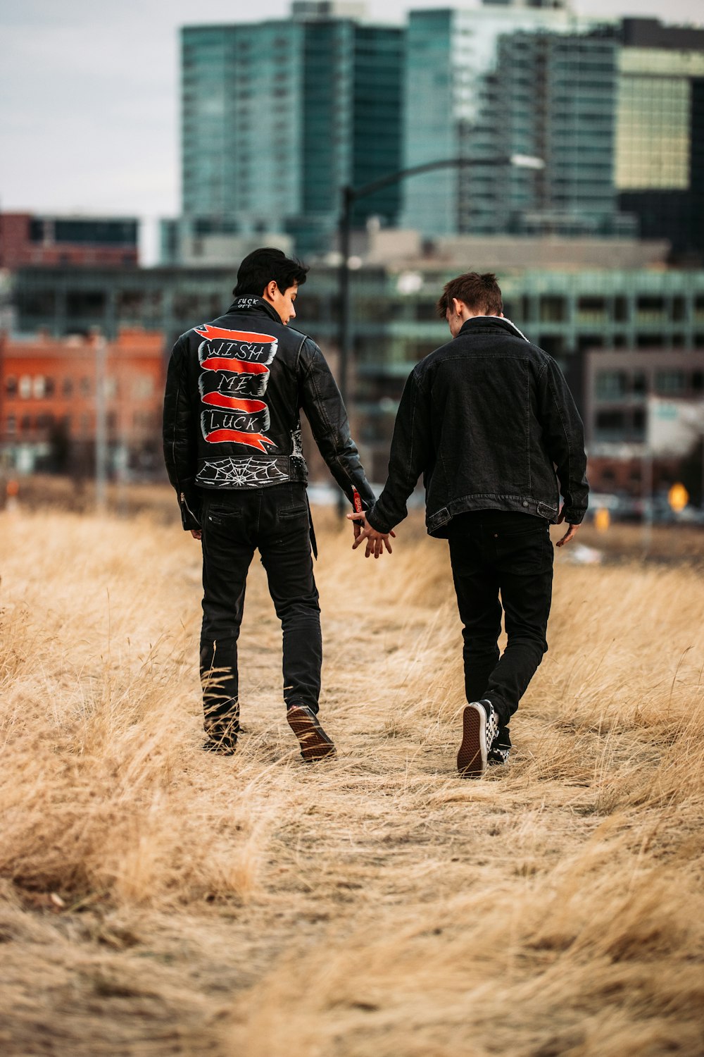 man in black jacket and black pants walking on brown field during daytime