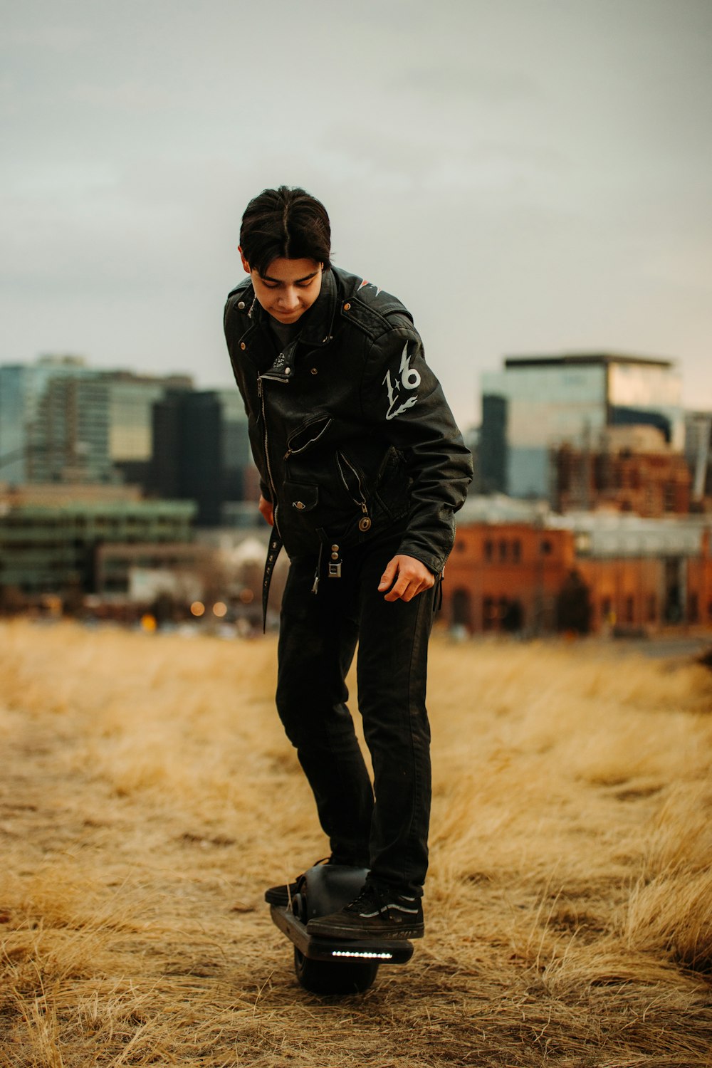 man in black jacket and black pants standing on brown field during daytime