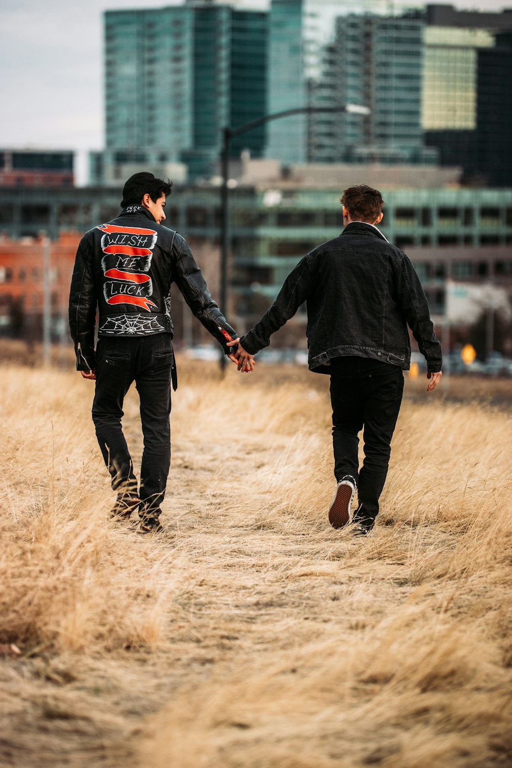 man in black jacket walking on brown field during daytime