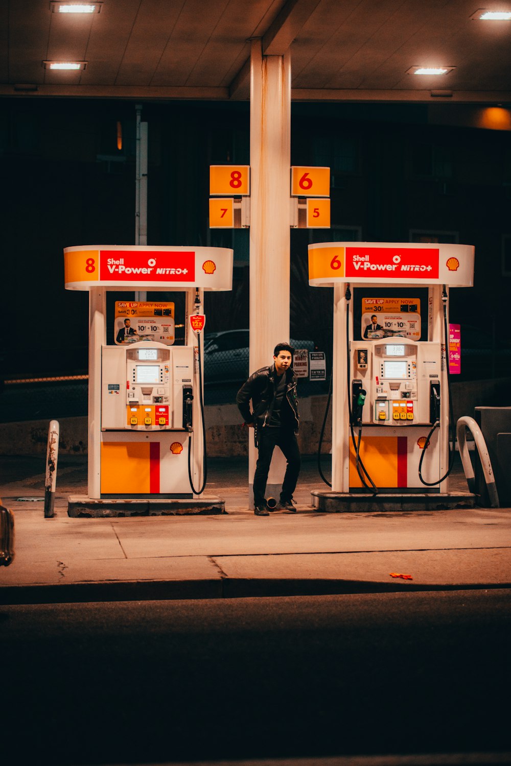 Foto homem na jaqueta preta de pé perto da bomba de gasolina branca e  vermelha – Imagem de Humano grátis no Unsplash