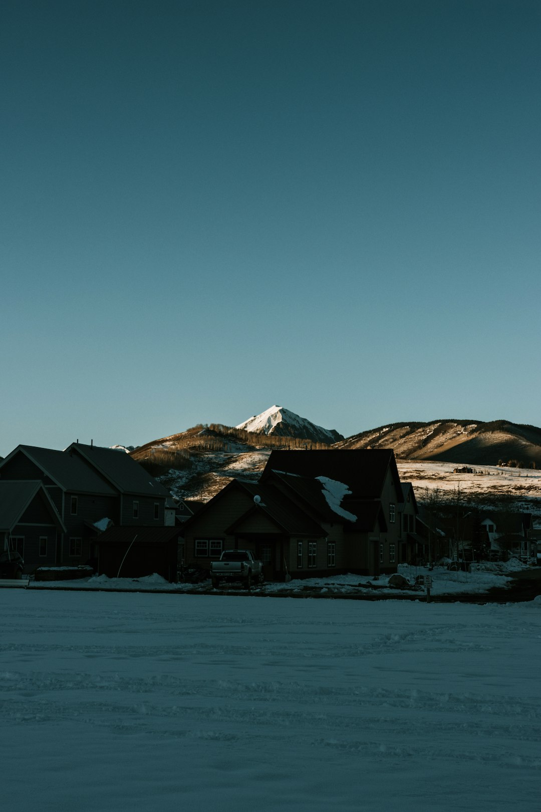 brown and white house near snow covered mountain during daytime