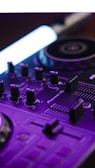 A close-up view of a DJ mixer with various control knobs and sliders. The equipment features intricate details highlighted by a purple hue and a distinct light source. The brand name 'Pioneer DJ' is visible on the surface.