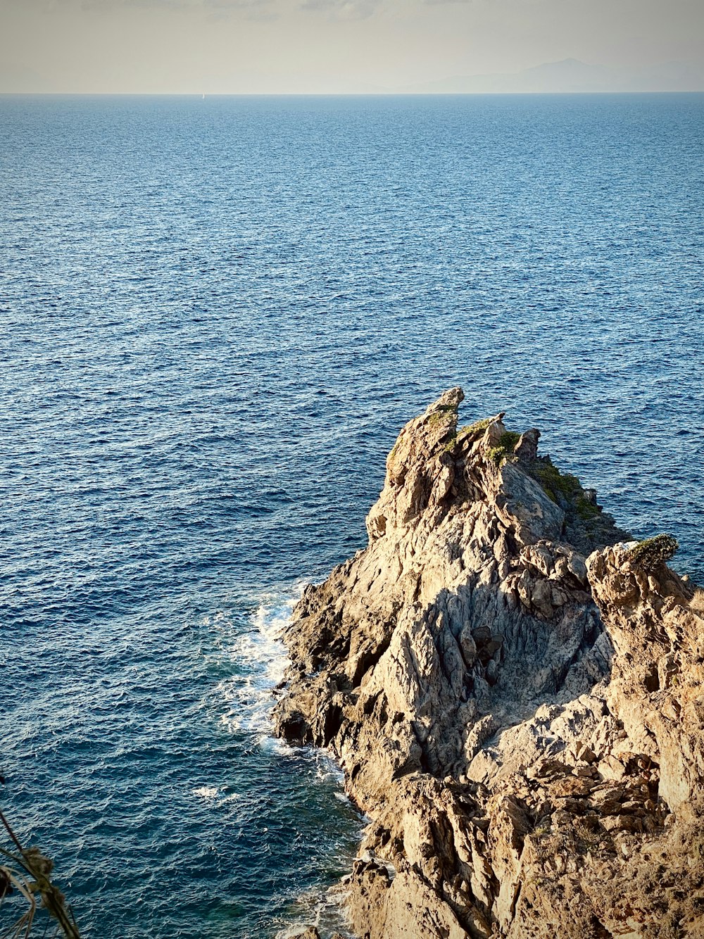 formação rochosa marrom no mar durante o dia