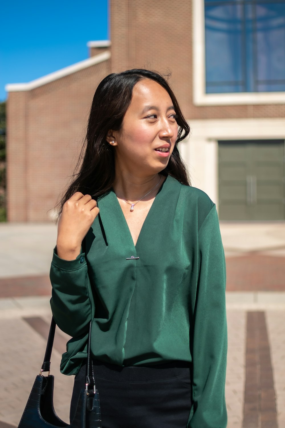 woman in green long sleeve shirt standing on sidewalk during daytime