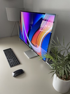 A modern monitor showing a vivid, high-resolution landscape wallpaper on a minimalist desk.
