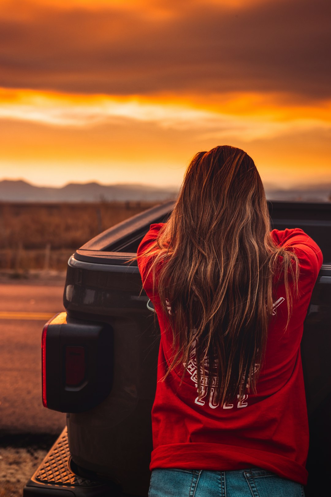 woman in red hoodie standing on brown field during sunset