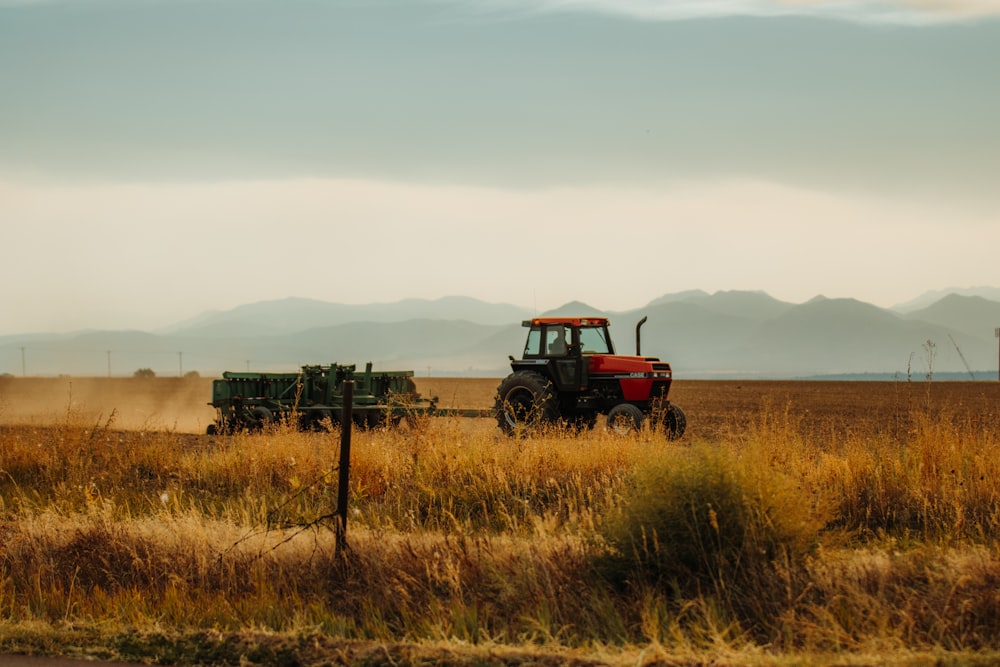 un tracteur et une remorque dans un champ avec des montagnes en arrière-plan