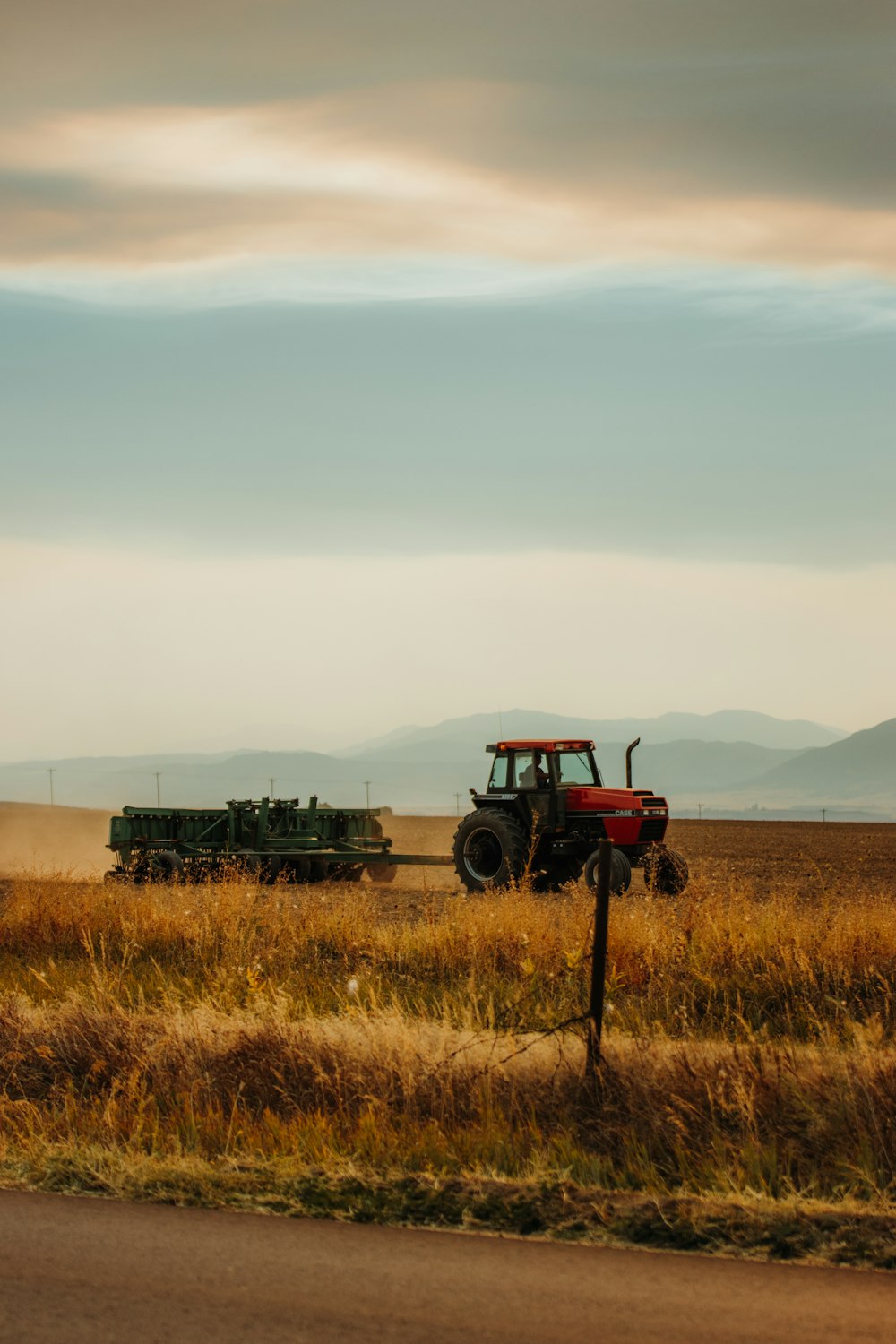 tracteur rouge et noir sur un champ d’herbe brune pendant la journée