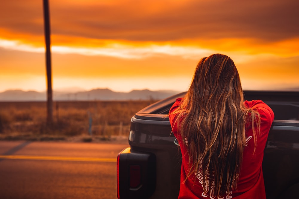 woman in red jacket standing on road during daytime