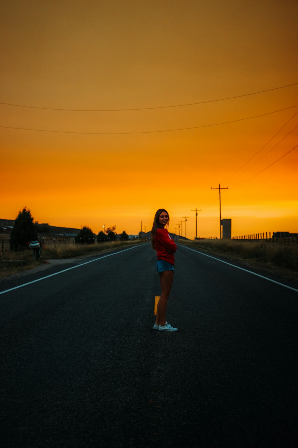 woman in red and blue plaid shirt standing on road during sunset